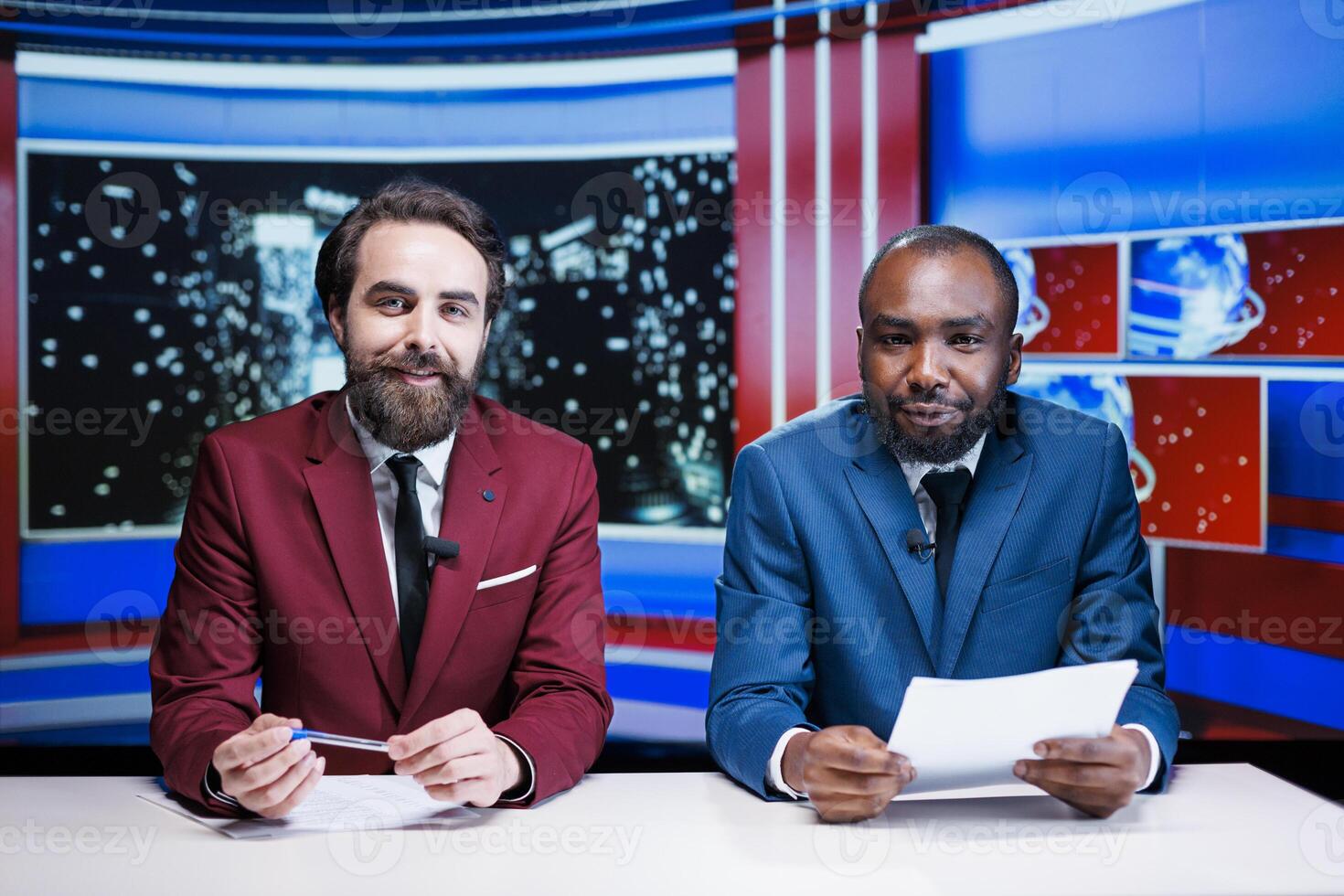 Journalists reporting latest news live on late night show, transmitting information about international events in newsroom. Diverse team of tv hosts working on media entertainment segment. photo