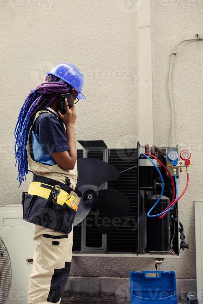 Qualified electrician on the phone with customer after finishing hvac system maintenance inspection. Trained engineer calling client to inform him about electrical issues found in condenser photo