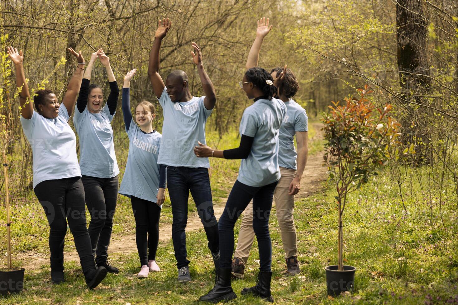 Team of diverse environmentalists linking hands to celebrate a successful mission of preserving natural habitat, saving the ecosystem. Group of people collaborate to grow more trees in the forest. photo