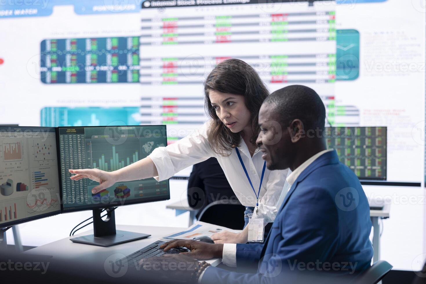 Diverse teammates examining statistics and infographics on computer in control room, joining forces to gather insight for business development. Analysts discussing legal changes. photo