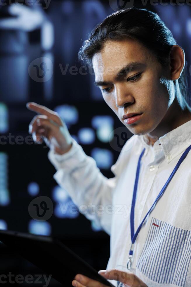Tech support worker between server cabinets electronics providing processing resources for companies worldwide. Competent developer fixes facility supercomputers used for storing large databases photo