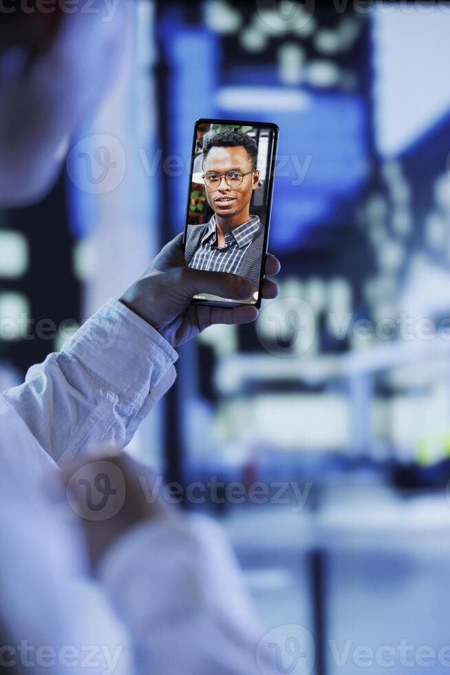 Woman in videocall with boyfriend while strolling around city streets at night, close up. Citizen using smartphone to show partner surroundings in dimly illuminated town center in blurry background photo