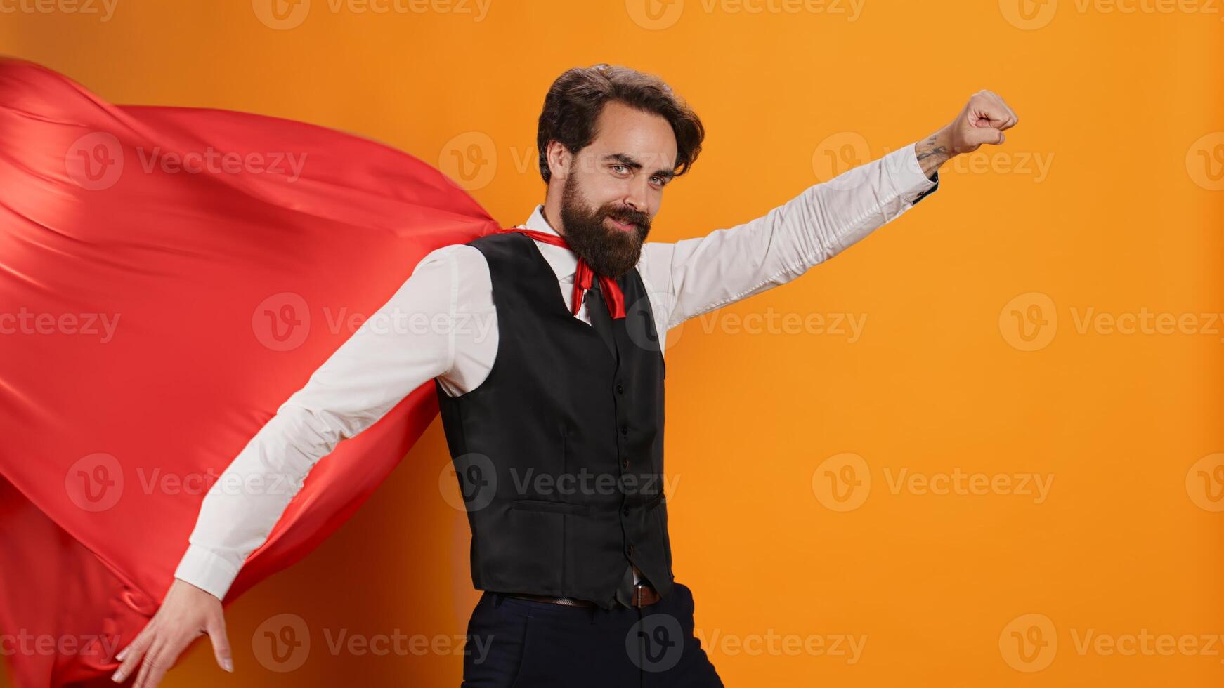 Confident waiter with red hero cape posing as a superhero on camera, determined to serve clients. Superhuman restaurant employee serving food and drinks, hero character costume with mantle. photo