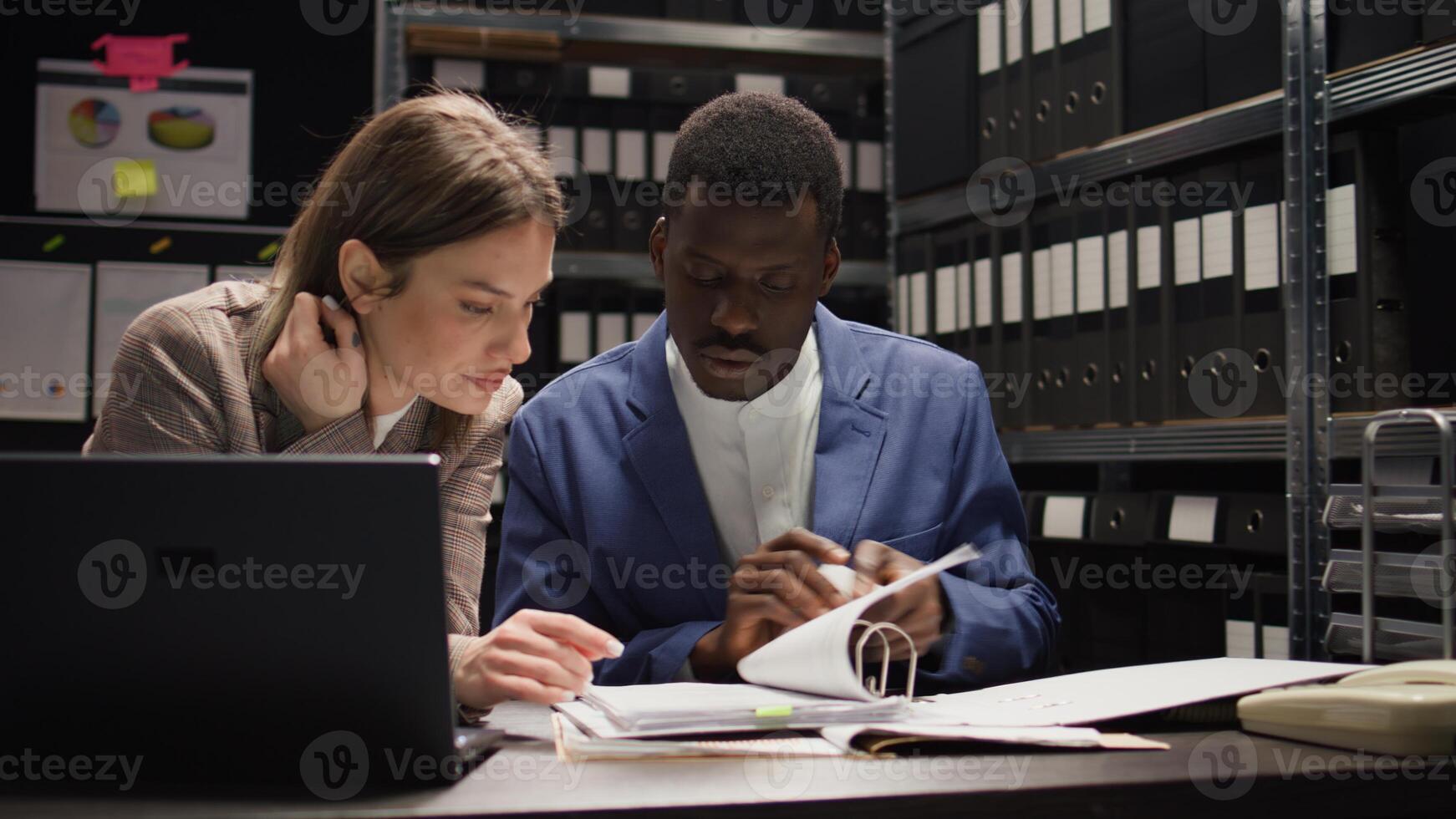 Multiethnic team of private detectives conducts a discreet inquiry, analyzing evidence and investigating records. Caucasian and african american investigators collaborate in office to solve crimes. photo