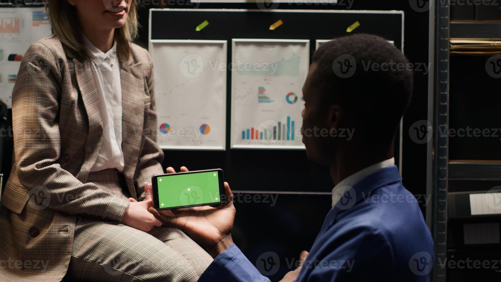 Private investigator looking at isolated copyspace display while horizontally holding smartphone with greenscreen. In evidence room, policeman utilising chromakey mockup template on mobile device. photo