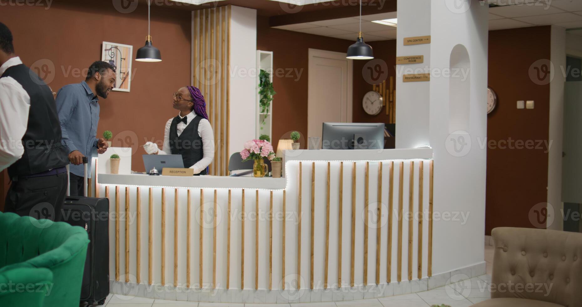 Hotel guest getting room access card after check in procedure at reception entrance, meeting with front desk employee asking about services. African american man travelling on vacation. photo