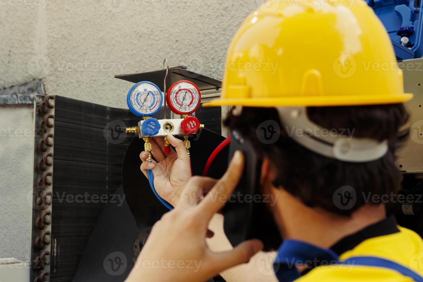 Expert repairman speaking over the phone with business owner, reporting found freon leaks leading to worse cooling efficiency after meticulous investigation during outside air conditioner checkup photo