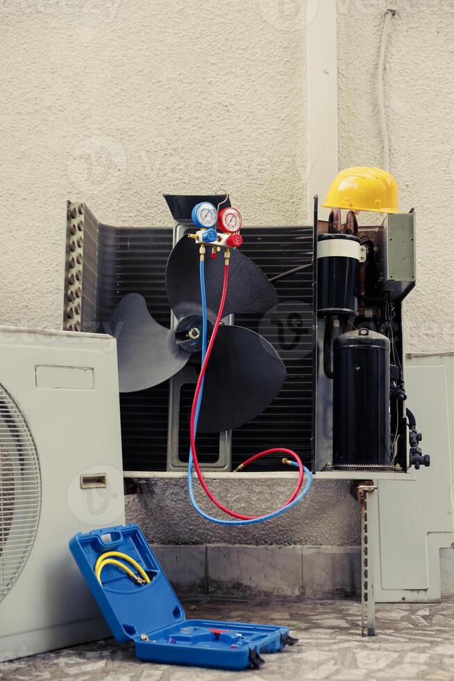 Faulty outdoor air conditioner system with protection cover removed in need of mending, with defective electric internal parts. External HVAC system not functioning anymore, ready to be repaired photo