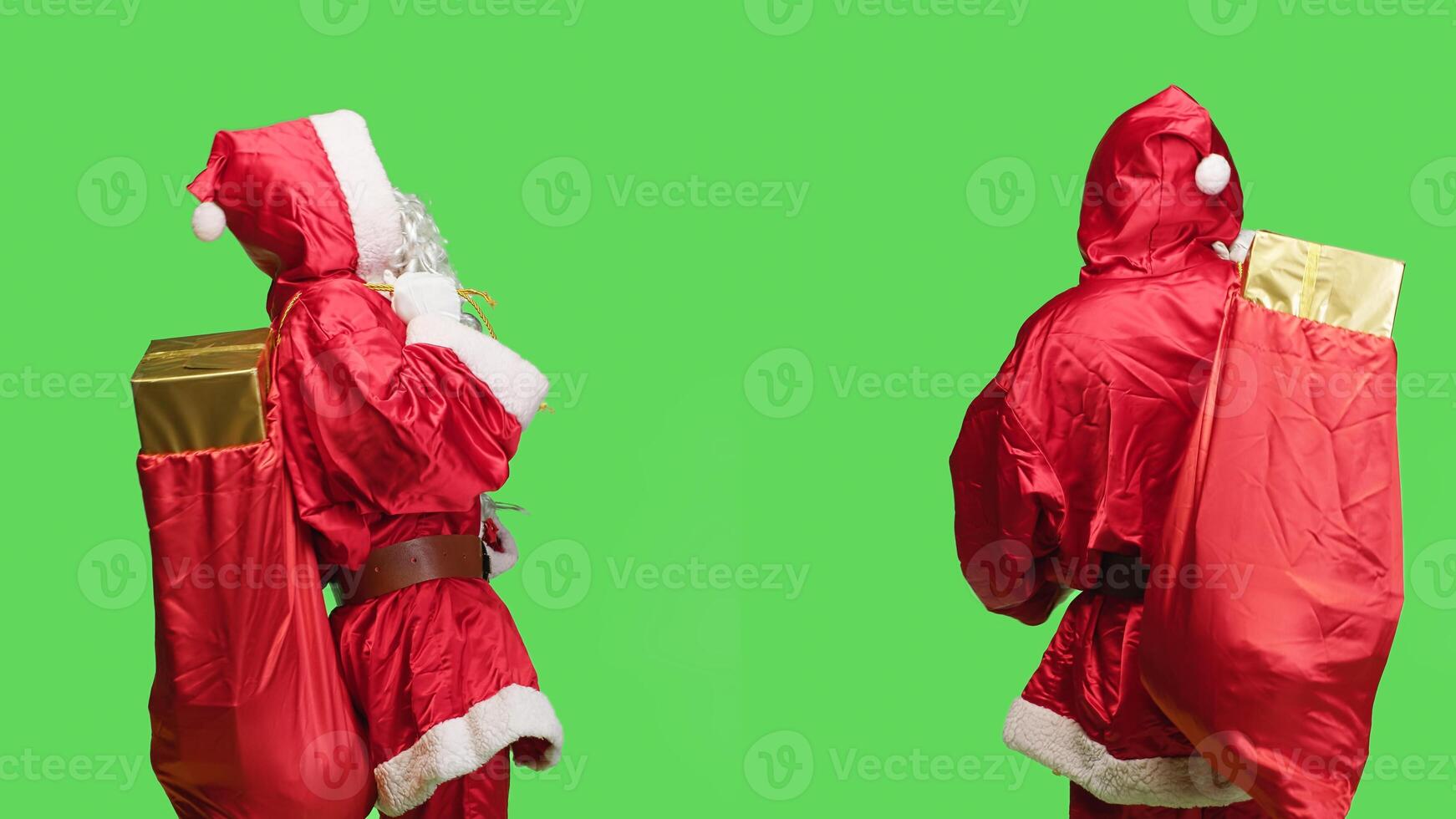 Father christmas carry iconic toy bag in studio, working to deliver presents in boxes with ribbon for kids. Santa claus with huge sack of gifts posing over isolated greenscreen background. photo