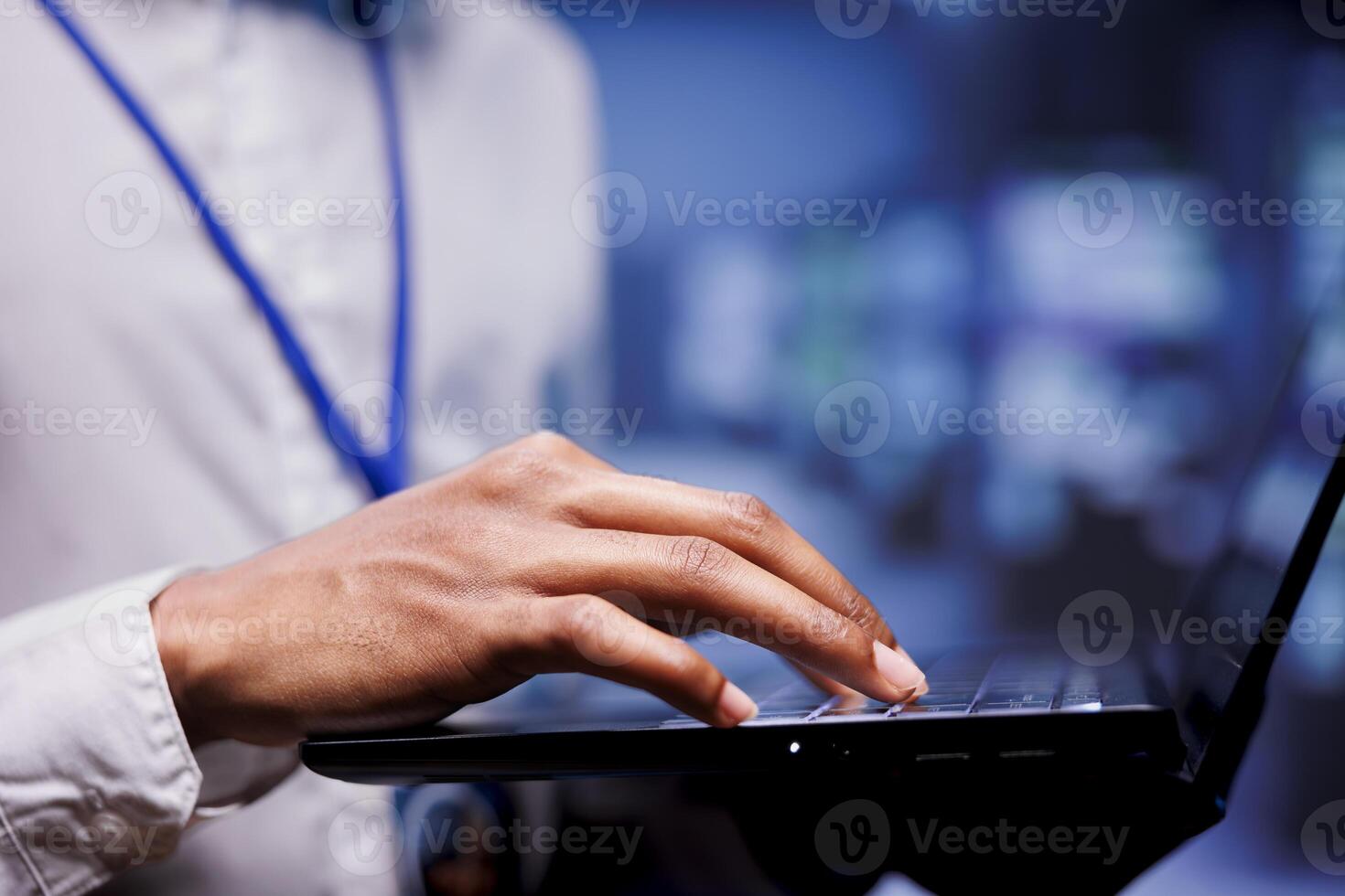 Expert doing server racks maintenance using laptop, close up. Engineer in high tech facility housing supercomputers, storage devices and networking parts providing vast amounts of computing resources photo