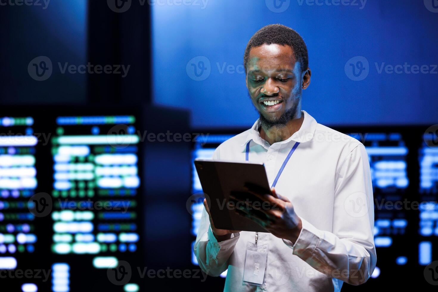 Cheerful manager using tablet to oversee energy consumption across server hub components and distributors. Expert ensuring high tech facility sensors for temperature and humidity are working properly photo