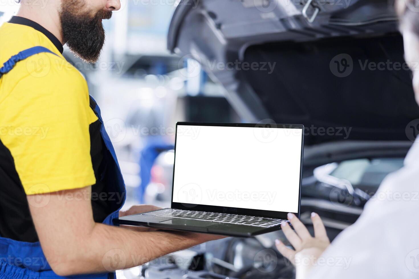 Certified engineer in garage using mockup laptop to follow checklist while doing maintenance on car. Adept worker in auto repair shop does checkup on vehicle helped by isolated screen device photo
