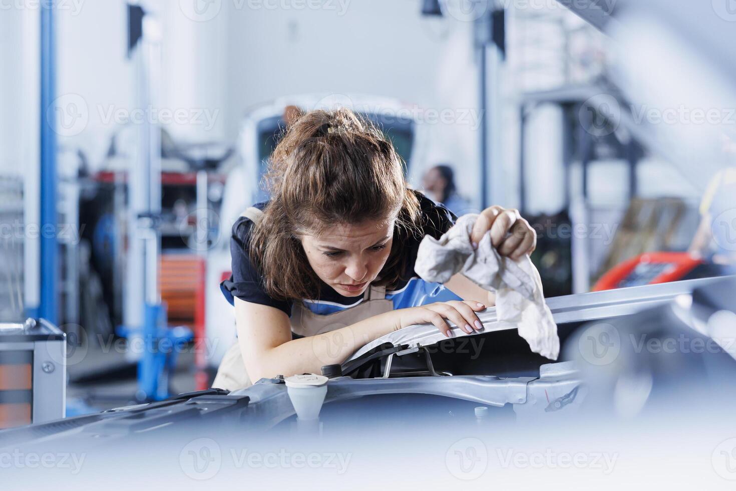 Meticulous engineer cleaning spillage after using oil extractor tool to change old car transmission fluid with new one in repair shop. Garage expert using professional equipment to do vehicle cleanup photo