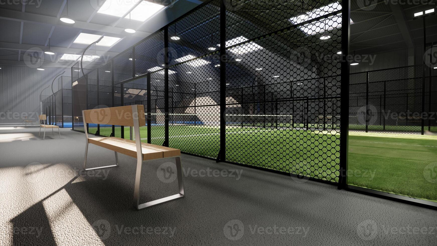 bench at empty green padel tennis courts inside a warehouse building, situated in the sports complex facility area. With lighting fixtures illuminated during the day photo