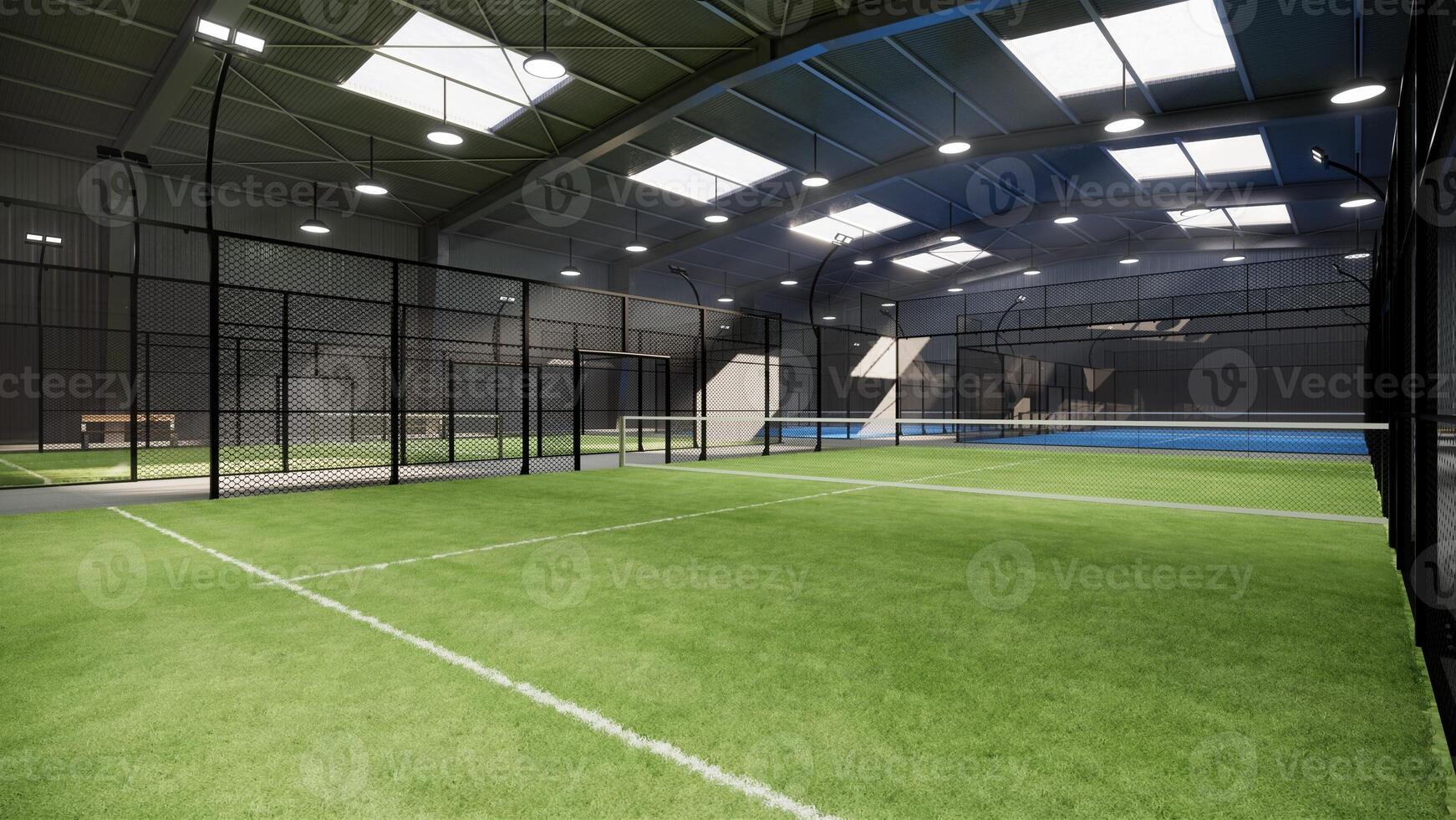 corner view of empty green padel tennis courts inside a warehouse building, situated in the sports complex facility area. With lights on during the day photo