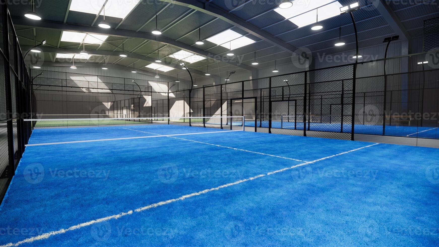 corner of blue padel tennis courts inside a warehouse building, located in the sports complex facility area. With lights still on despite it being daytime photo