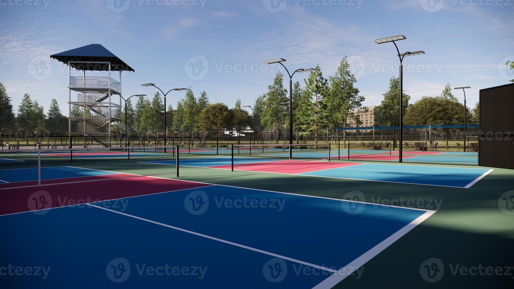 Empty pickleball courts with floors in red, blue, and green colors and white lines, equipped with lights, fencing, seating, and surrounded by trees photo