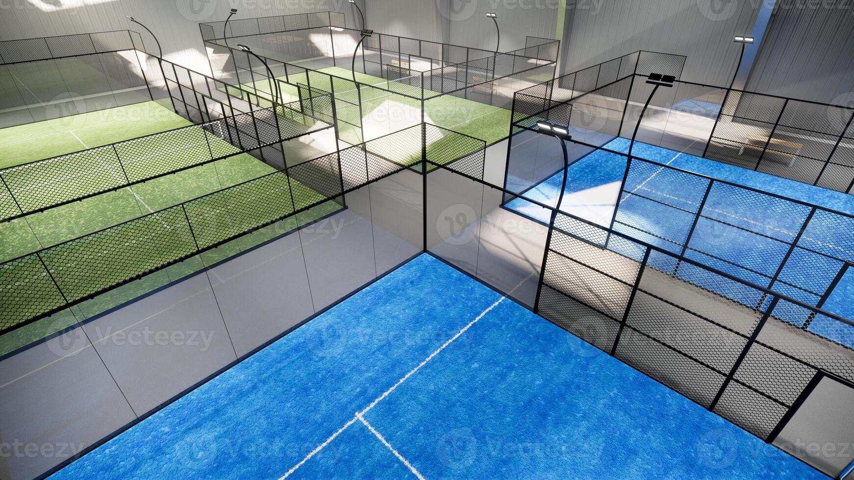 aerial view of empty green and blue padel tennis courts inside a warehouse building, situated in the sports complex facility area. With lighting fixtures illuminated during the day photo