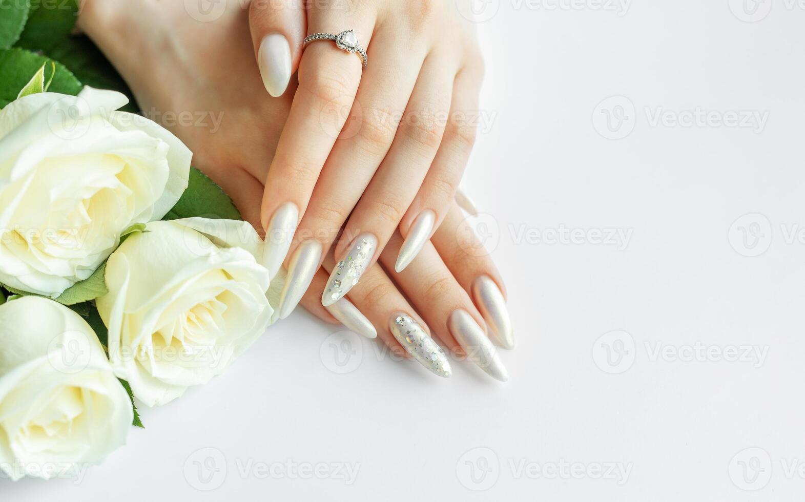 Female Hands on a white background with beautiful pearl manicure and white roses photo