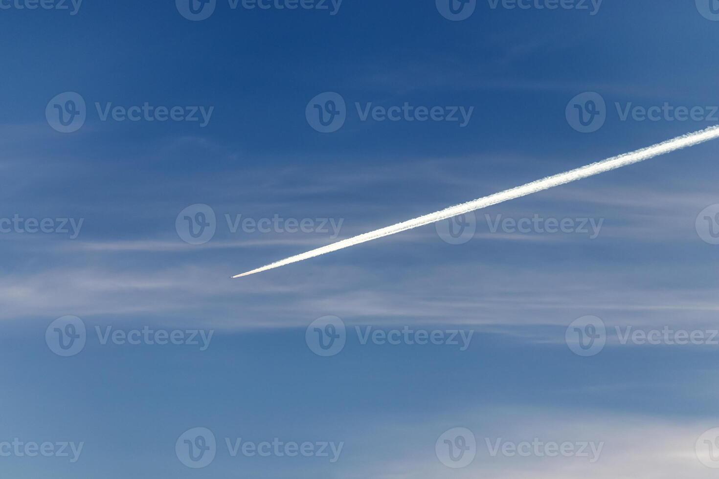 Contrails - one flying transport airplane with condensation trails in a blue sky photo