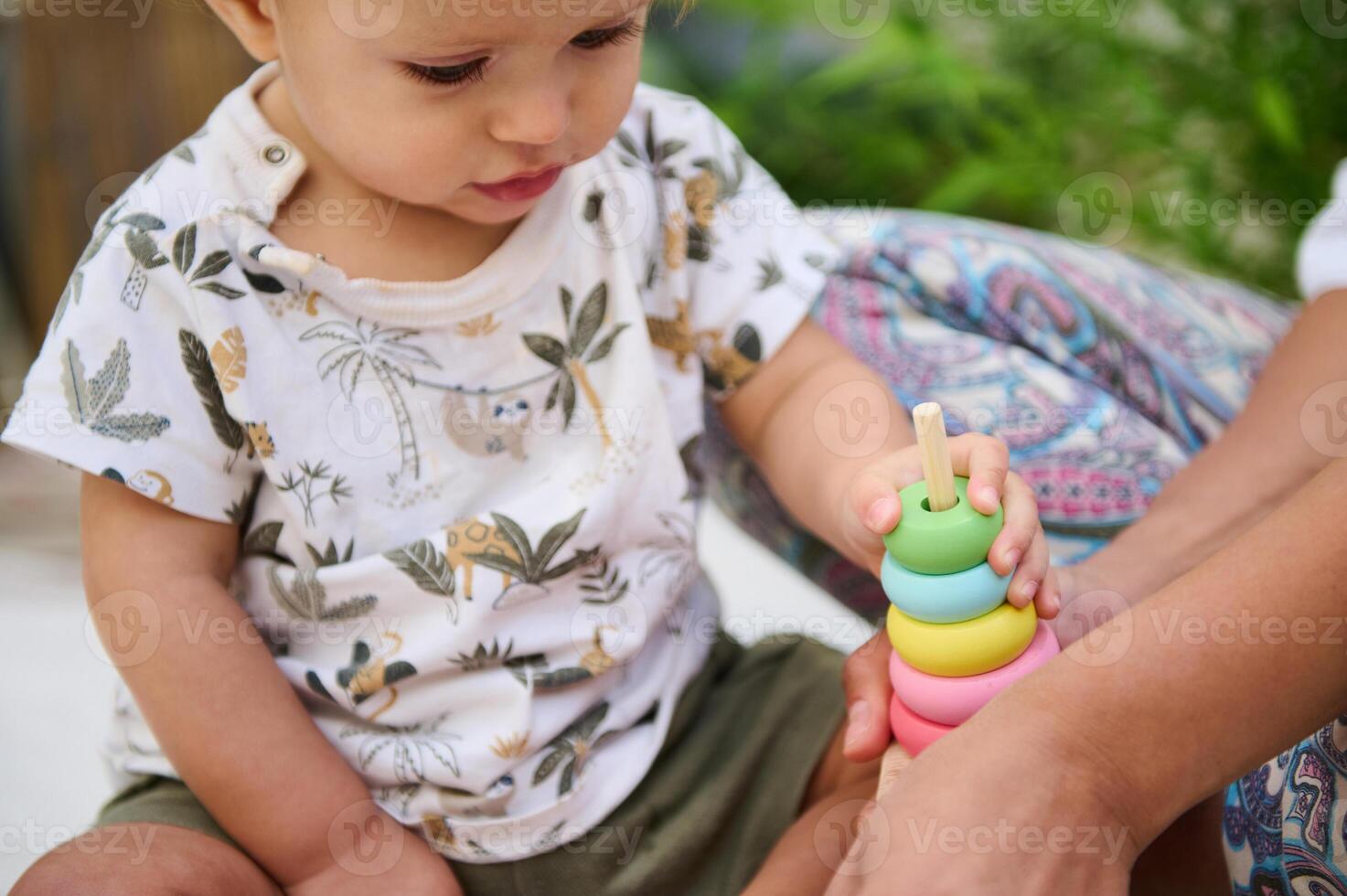 Selective focus on the hand of baby boy on colorful wooden circles of a pyramid, playing educational and developmental games, developing motor skills and thinking. Childhood and Kids entertainment photo
