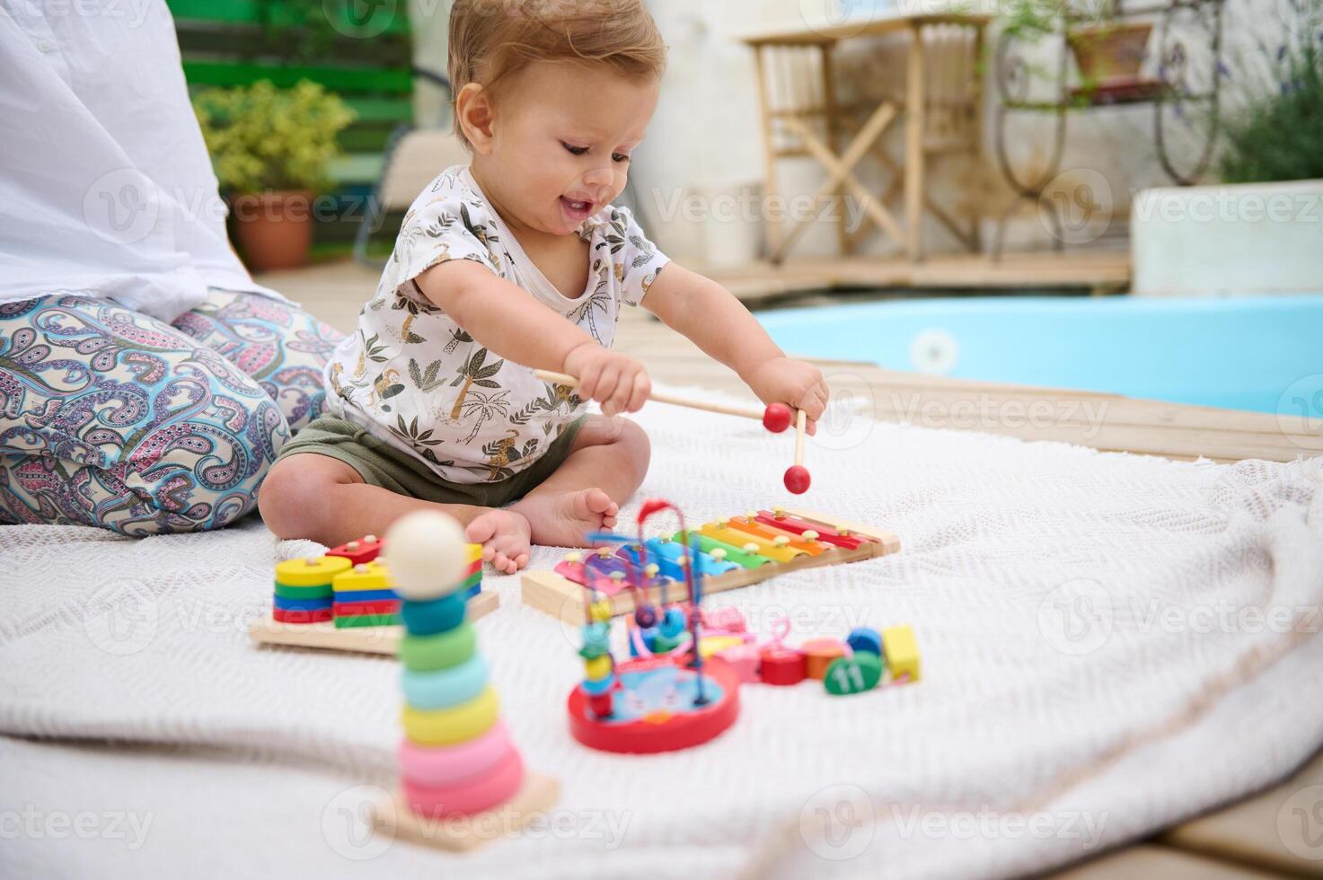 Happy baby playing with toys outdoors by the poolside photo