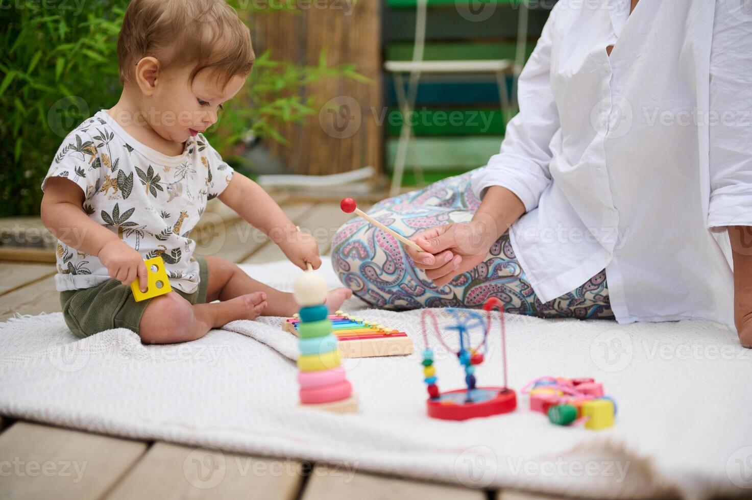 Mother and baby playing with toys on a wooden deck photo