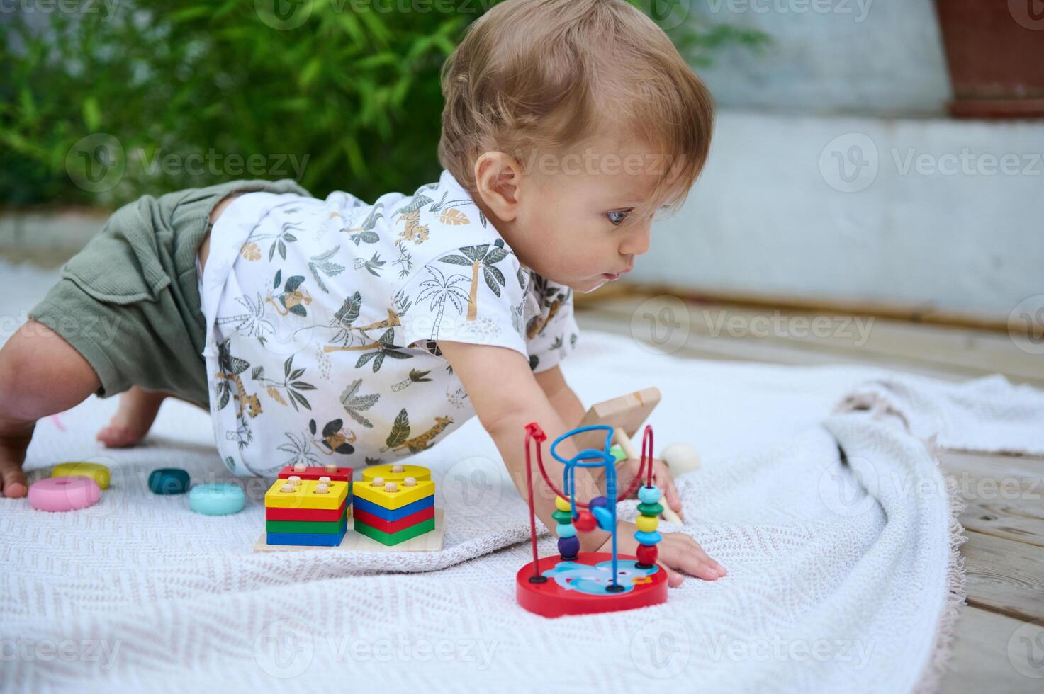 Curious toddler playing with colorful educational toys on a blanket photo