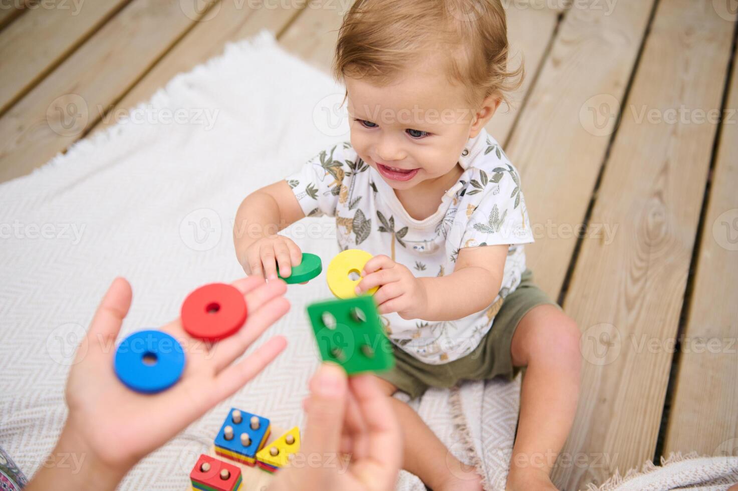 Toddler playing with colorful educational toys on wooden deck photo