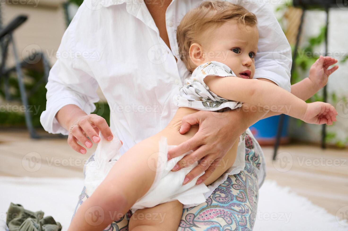 Mother changing baby's diaper in outdoor setting photo
