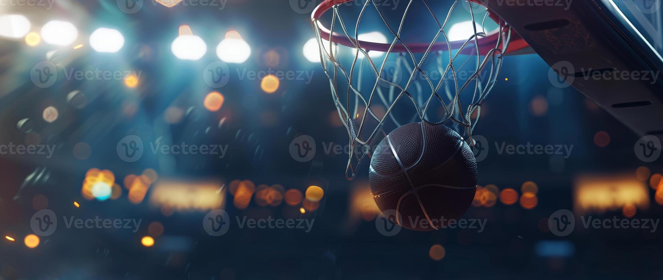 Close-up shot of a basketball going through the hoop during a game with stadium lights and a blurred crowd in the background. photo