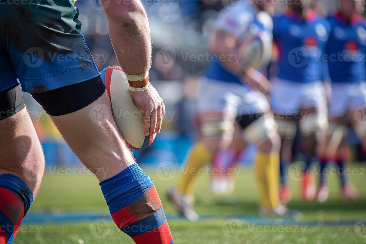 Close-up of rugby player holding ball during match, with teammates in the background on green field, blue and yellow uniforms. photo