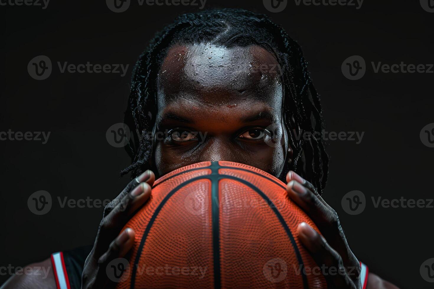 Intense portrait of a basketball player holding a ball against a dark background, showcasing focus and determination in sports. photo