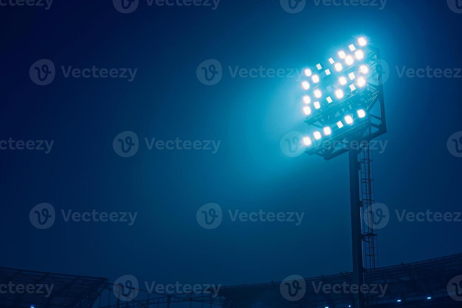 Bright stadium floodlights illuminating a sports field at night against a dark blue sky, creating a dramatic and vibrant atmosphere. photo