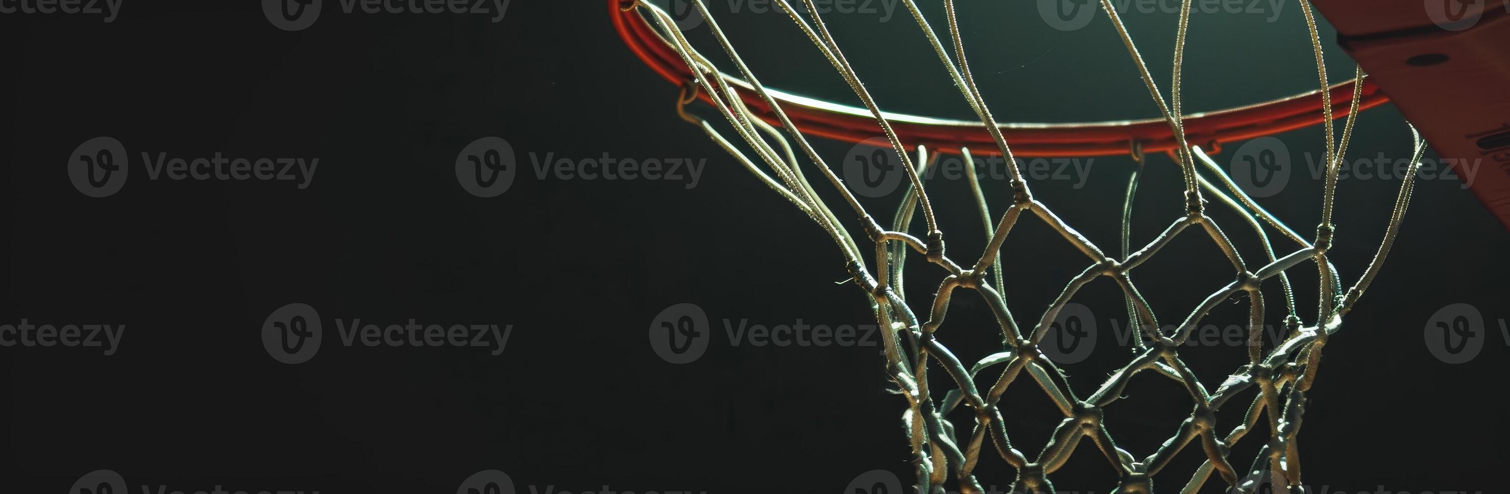 Close-up of a basketball hoop and net in a dimly lit gymnasium, capturing the details of the net and rim. photo