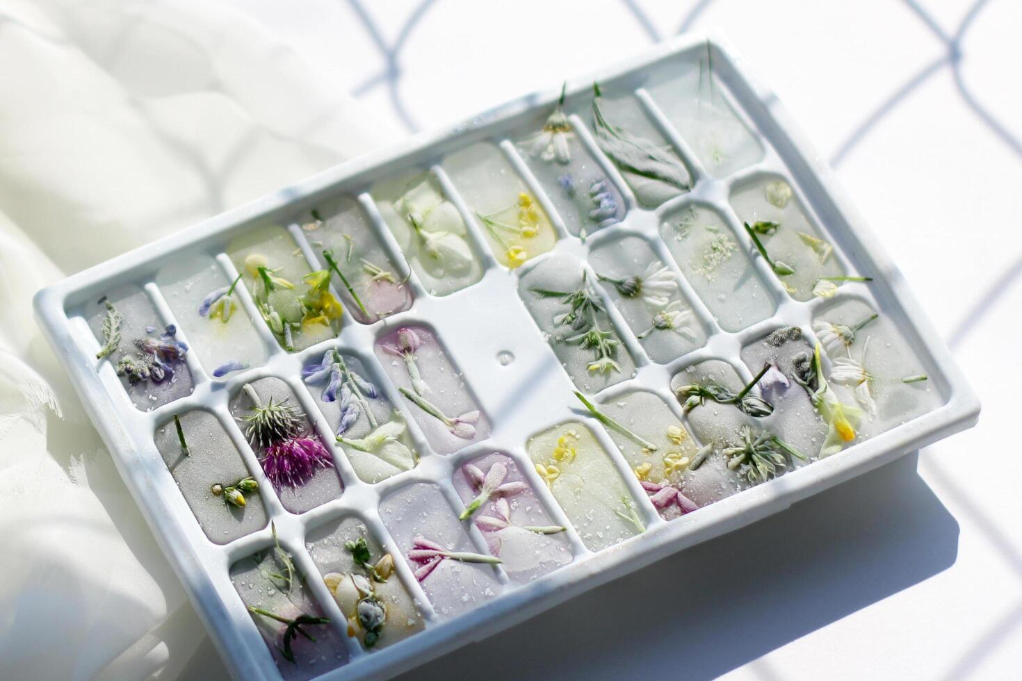 ice mold with frozen flowers. Ice cubes for cooling on a summer day photo