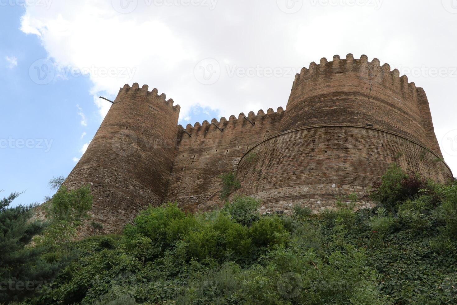 The old brick castle on the green rocky mountain photo