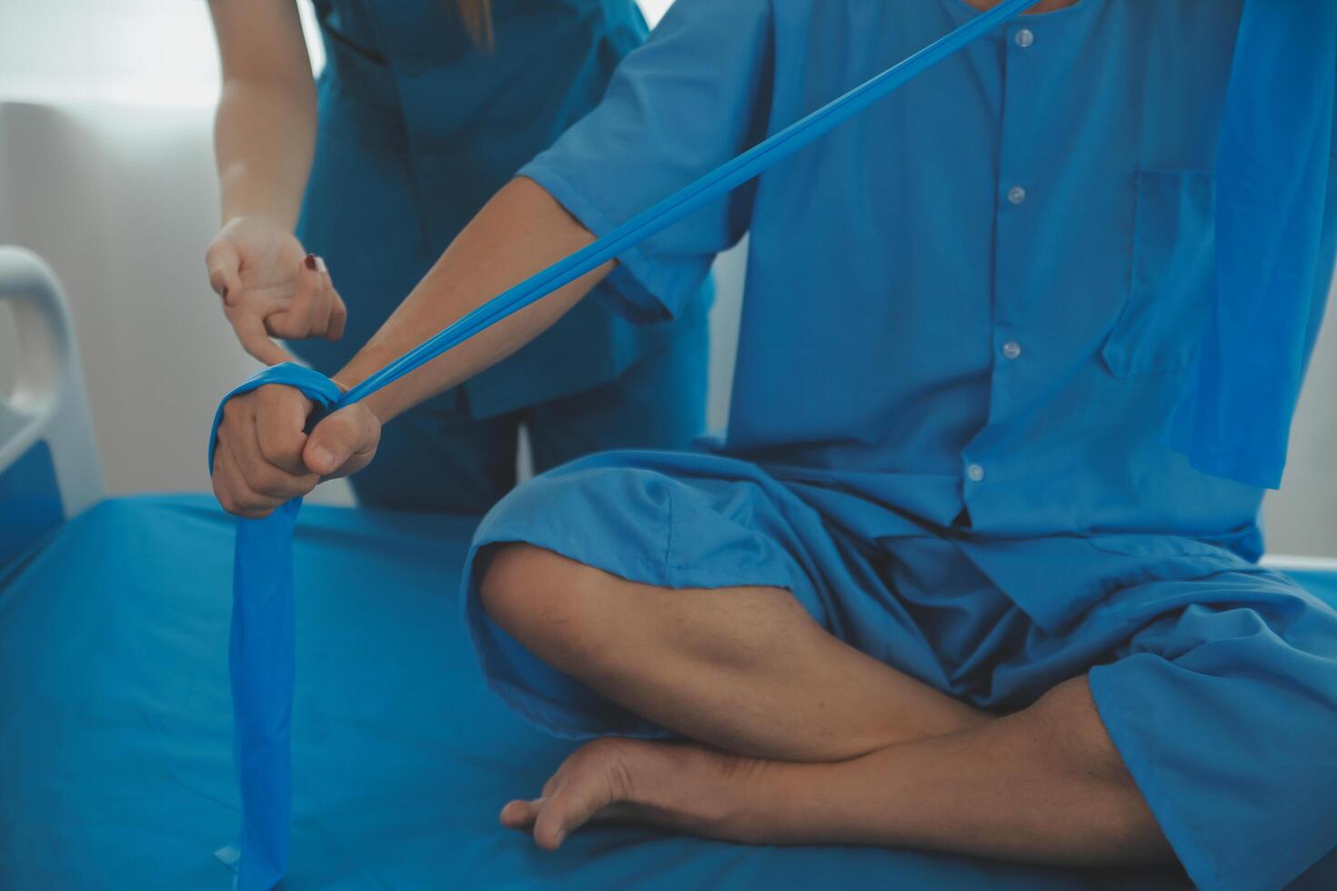 Close up hand patient doing stretching exercise with a flexible exercise band and a physical therapist hand to help in clinic room. photo