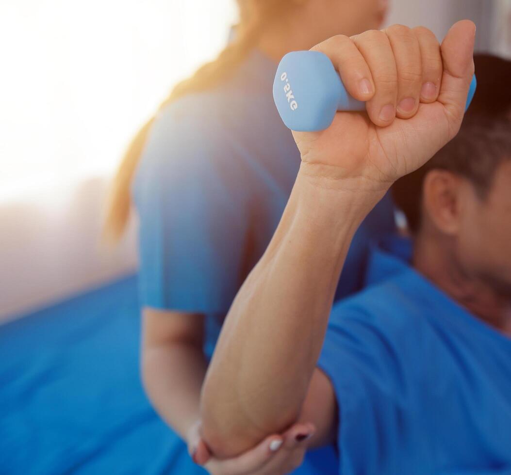 Physiotherapist man giving exercise with dumbbell treatment About Arm and Shoulder of athlete male patient Physical therapy concept photo
