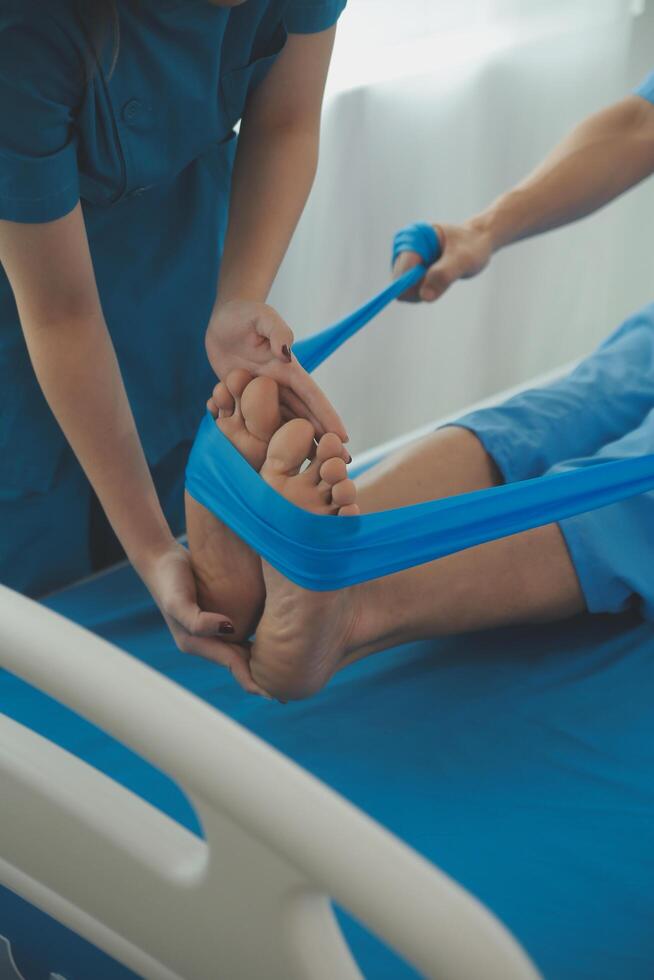 Professional orthopedist examining the little patient's leg in the clinic. Patient at the physiotherapy doing physical exercises with his therapist photo
