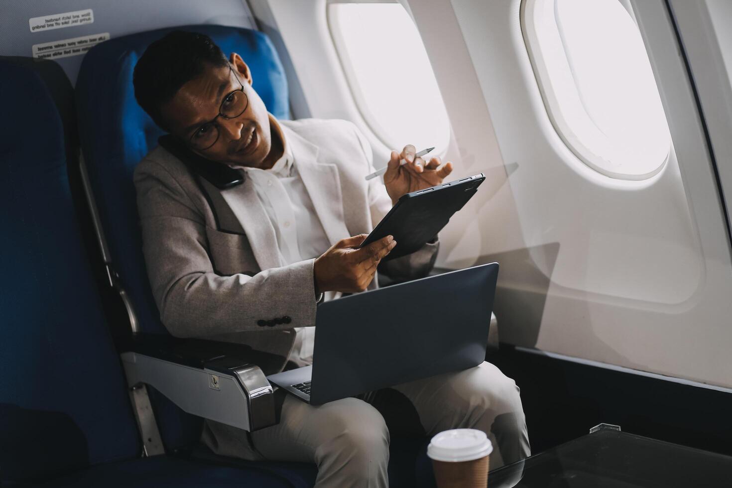 Airplane, travel and portrait of businessman working on laptop computer and smartphone while sitting in airplane. photo