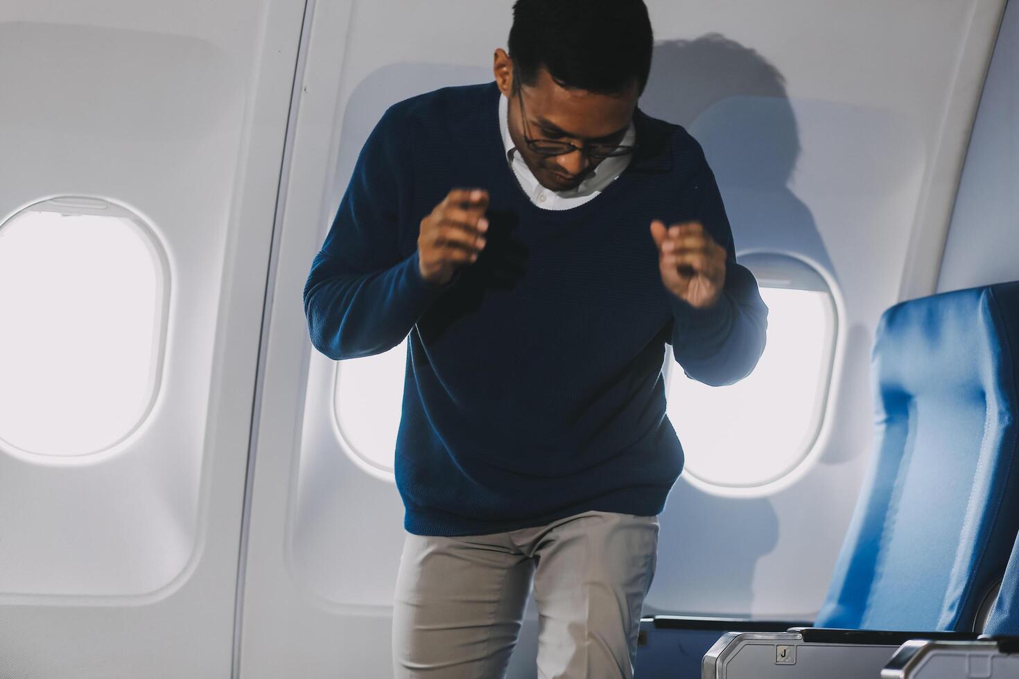 Side view millennial businessman drinking coffee, and using laptop while sitting comfortable seat on airplane cabin photo