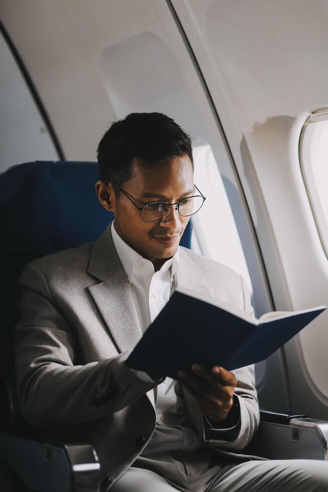 Airplane, travel and portrait of businessman working on laptop computer and smartphone while sitting in airplane. photo