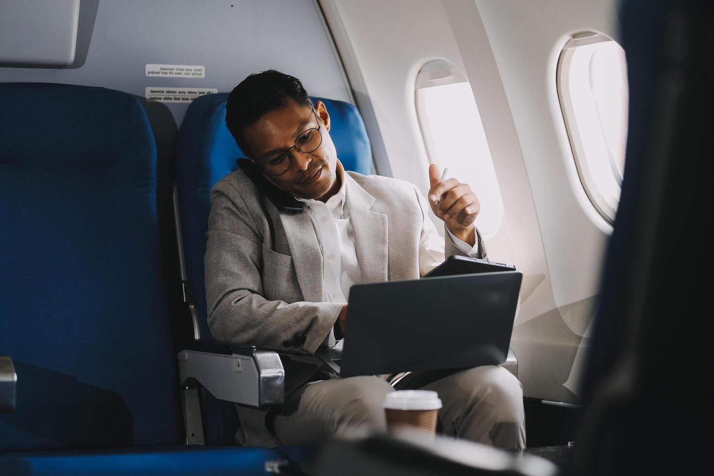 Airplane, travel and portrait of businessman working on laptop computer and smartphone while sitting in airplane. photo