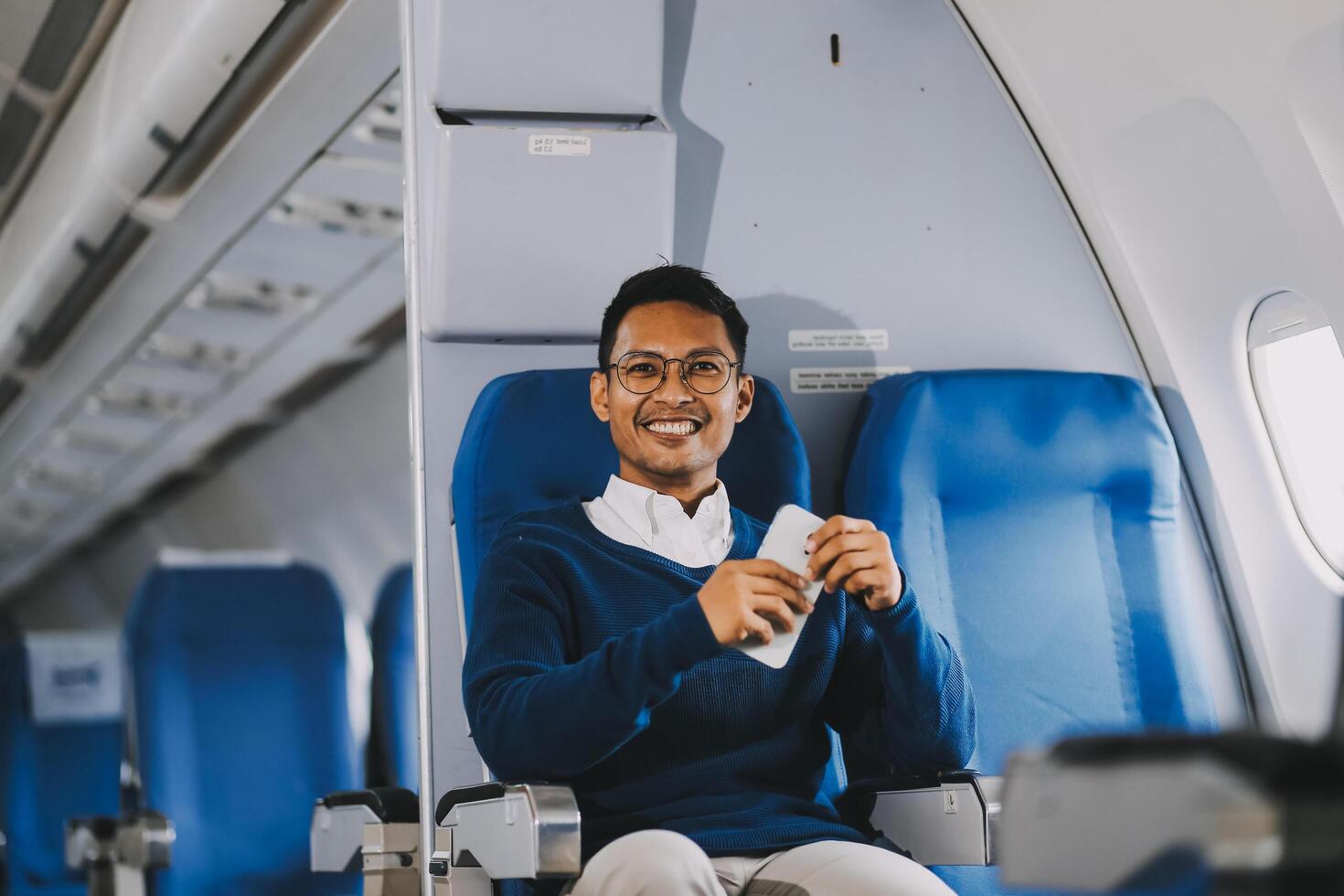 Man with dark hair is reading text message on mobile phone and speaking by phone during flying in the airplane photo