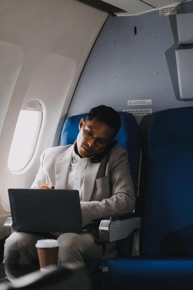 Airplane, travel and portrait of businessman working on laptop computer and smartphone while sitting in airplane. photo