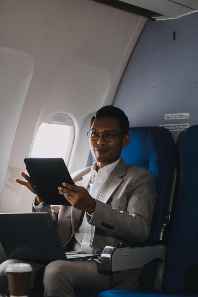 Airplane, travel and portrait of businessman working on laptop computer and smartphone while sitting in airplane. photo