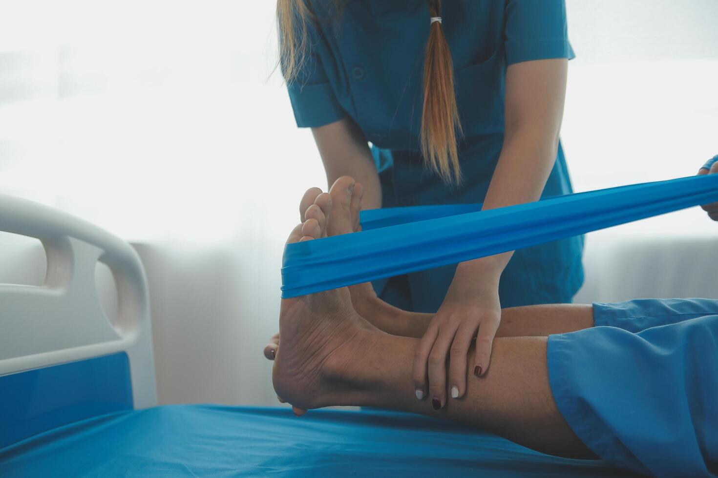 Professional orthopedist examining the little patient's leg in the clinic. Patient at the physiotherapy doing physical exercises with his therapist photo