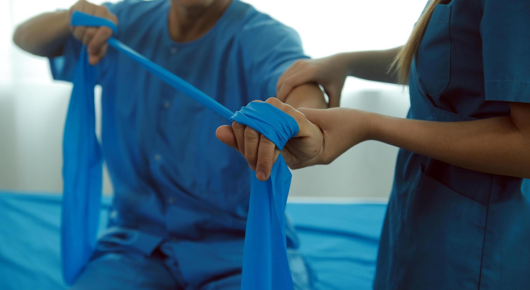Close up hand patient doing stretching exercise with a flexible exercise band and a physical therapist hand to help in clinic room. photo