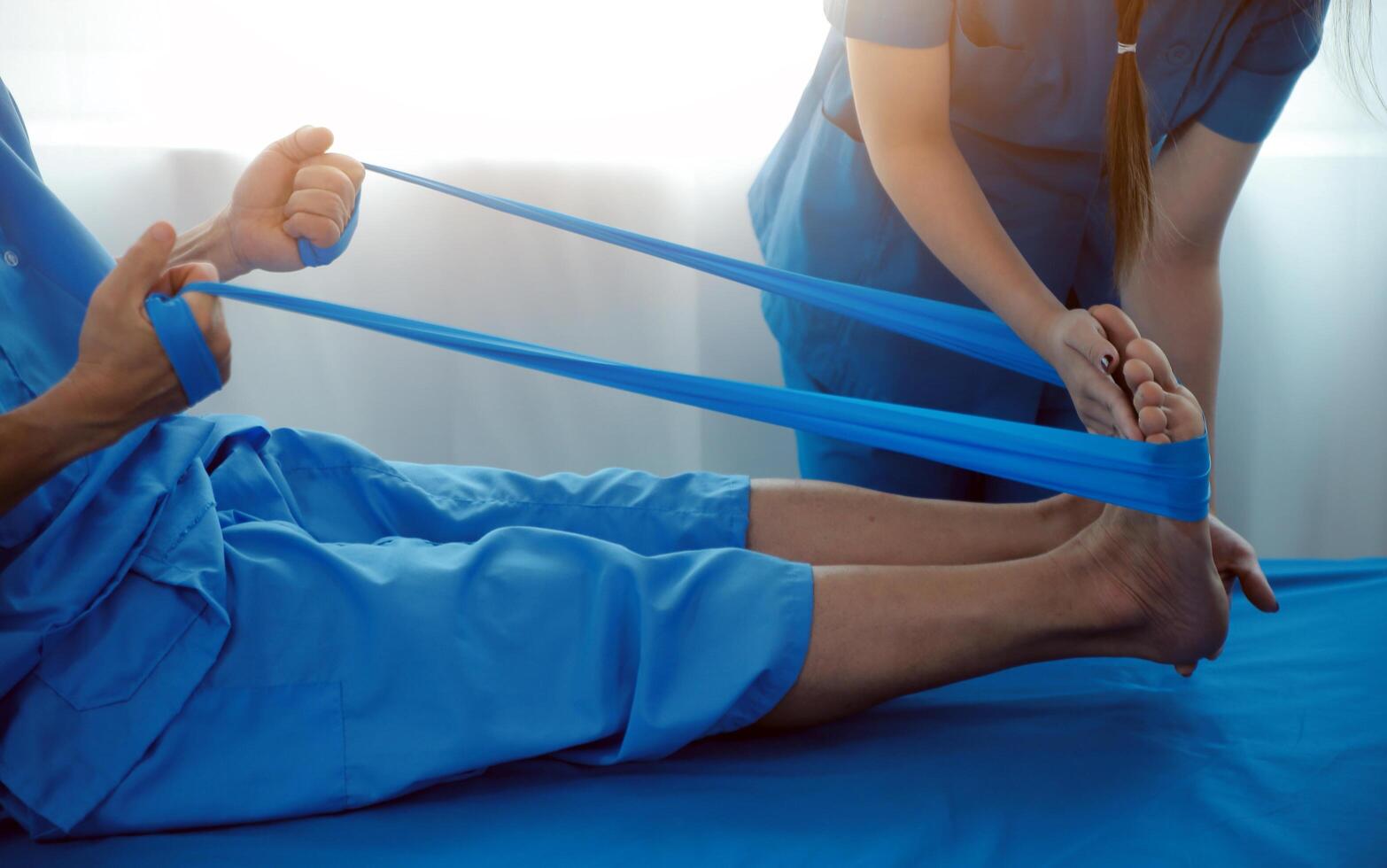 Professional orthopedist examining the little patient's leg in the clinic. Patient at the physiotherapy doing physical exercises with his therapist photo